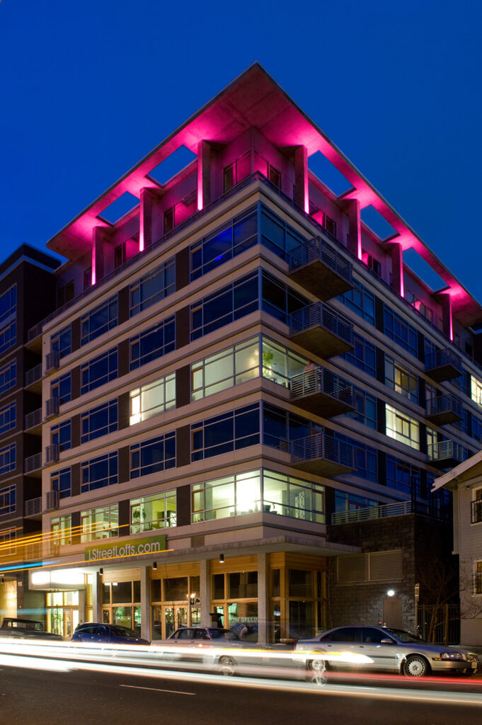 an image of the L Street Lofts taken during the evening with pink light illuminating from the top of the structure