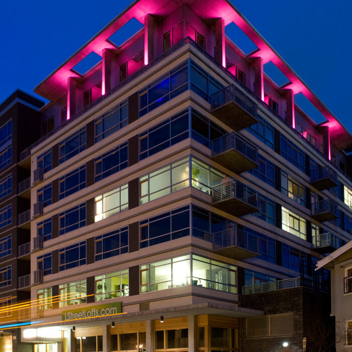 an image of the L Street Lofts taken during the evening with pink light illuminating from the top of the structure