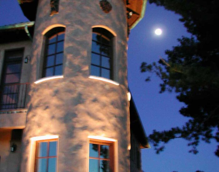 an image of a residential turret lit up at night with the moon in the sky
