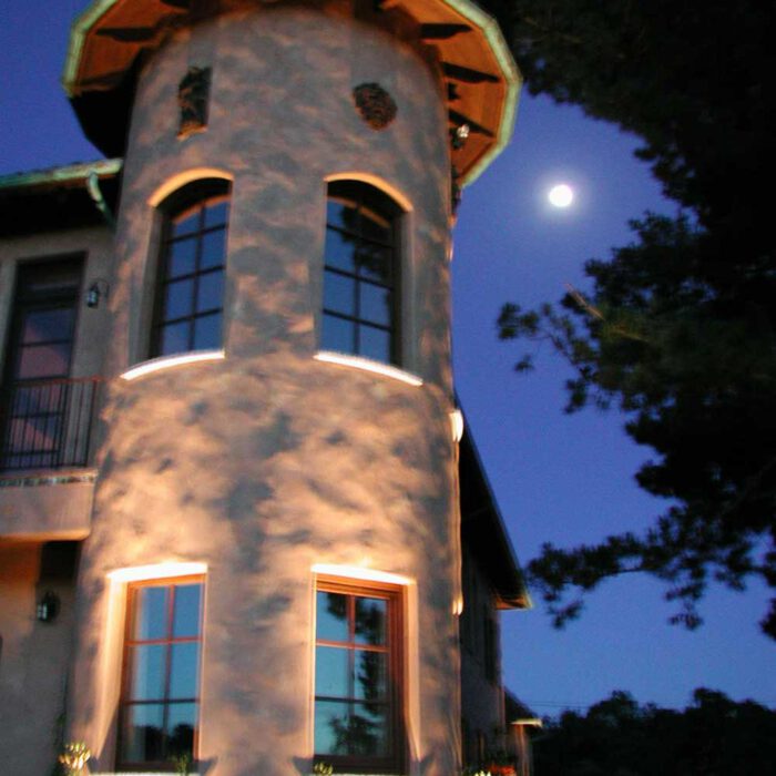 an image of a residential turret lit up at night with the moon in the sky
